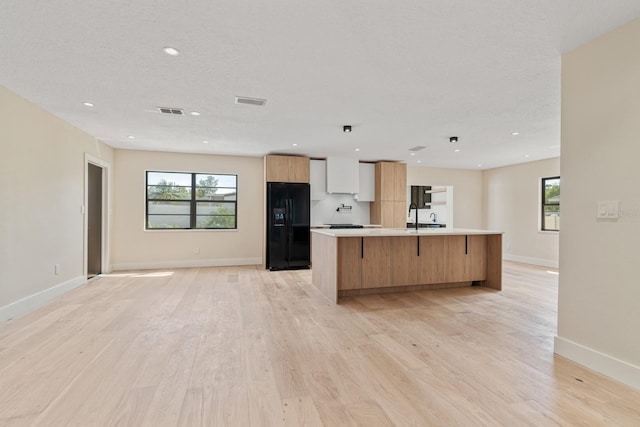 kitchen featuring modern cabinets, light wood-style flooring, open floor plan, and black refrigerator with ice dispenser