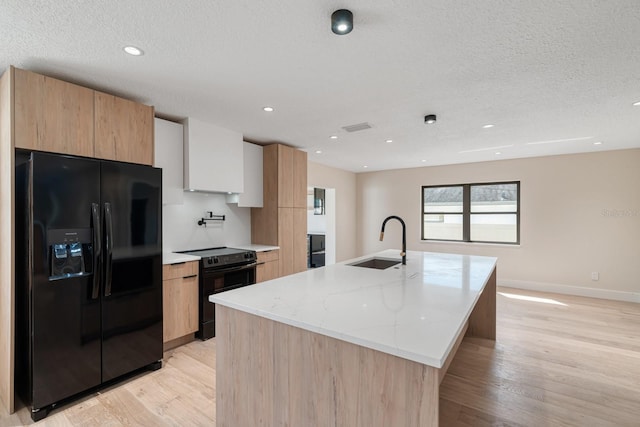 kitchen featuring black appliances, a sink, modern cabinets, light wood-style flooring, and a textured ceiling