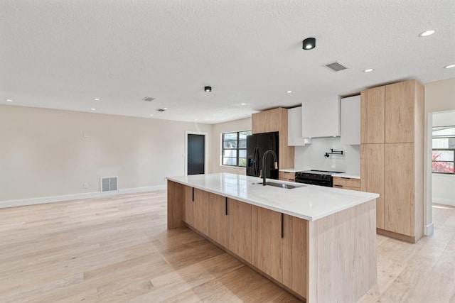 kitchen featuring a sink, modern cabinets, black appliances, light countertops, and light wood-style floors