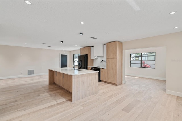 kitchen with black refrigerator with ice dispenser, modern cabinets, light wood-style floors, baseboards, and recessed lighting