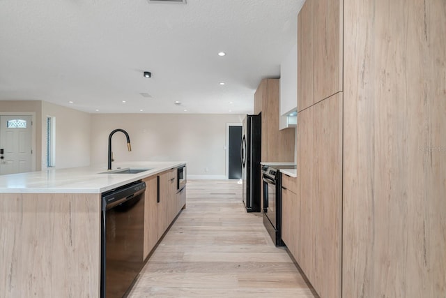 kitchen with a sink, modern cabinets, black appliances, light brown cabinets, and recessed lighting
