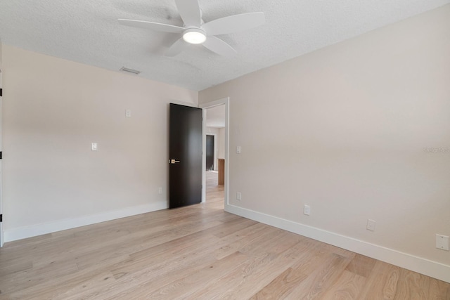 unfurnished room with light wood finished floors, a ceiling fan, baseboards, and a textured ceiling