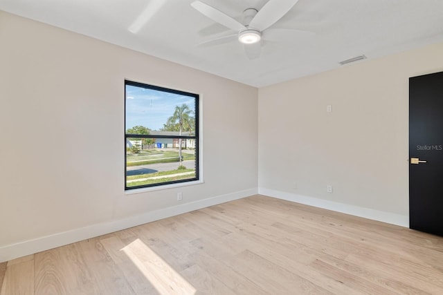 spare room featuring light wood-style floors, a ceiling fan, and baseboards