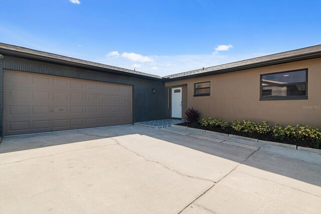 ranch-style house with driveway, an attached garage, and stucco siding