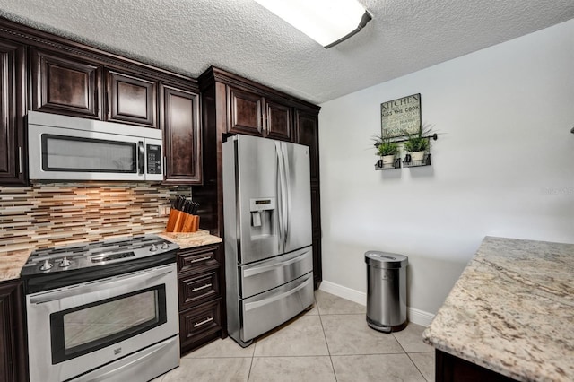 kitchen featuring light tile patterned floors, dark brown cabinets, appliances with stainless steel finishes, and decorative backsplash