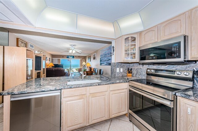 13000 Gulf Blvd Unit 109, Madeira Beach, FL 33708 - kitchen with stone counters, a peninsula, appliances with stainless steel finishes, a sink, and light brown cabinetry