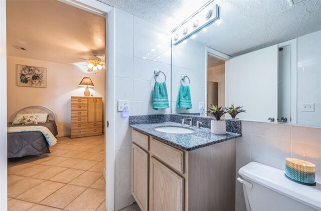 13000 Gulf Blvd Unit 109, Madeira Beach, FL 33708 - bathroom featuring toilet, tile patterned floors, tile walls, and a textured ceiling