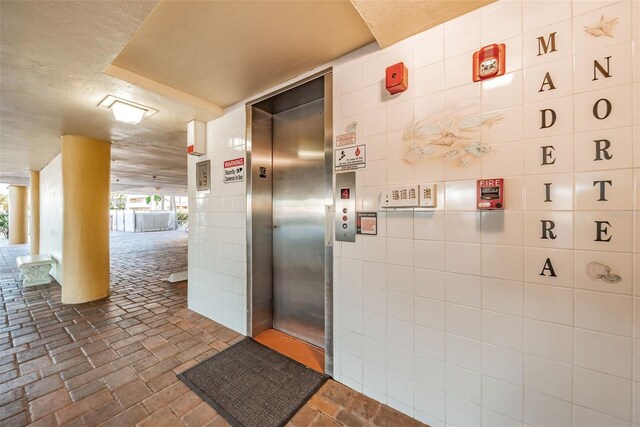 13000 Gulf Blvd Unit 109, Madeira Beach, FL 33708 - bathroom featuring brick floor, elevator, and tile walls