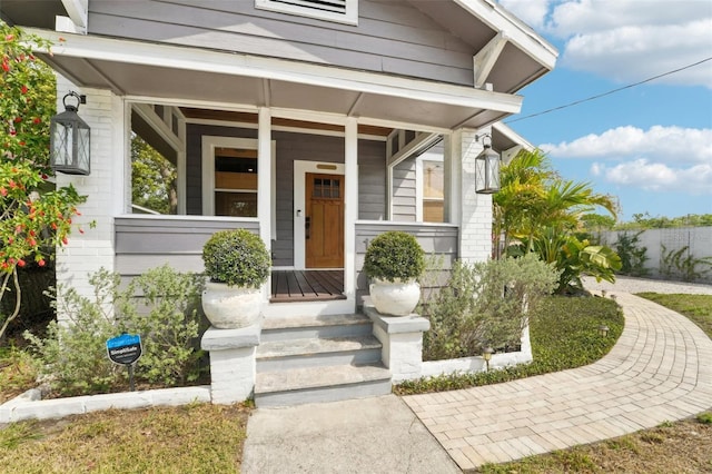 doorway to property with brick siding and a porch