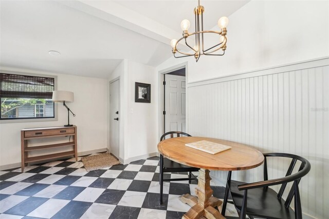 dining area with lofted ceiling, an inviting chandelier, baseboards, dark floors, and a wainscoted wall