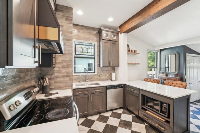 kitchen with light countertops, stainless steel appliances, a sink, a peninsula, and light floors