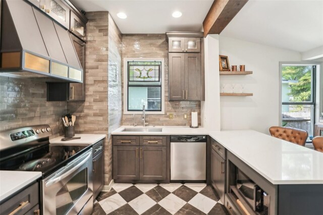 kitchen featuring light countertops, a sink, appliances with stainless steel finishes, a peninsula, and premium range hood