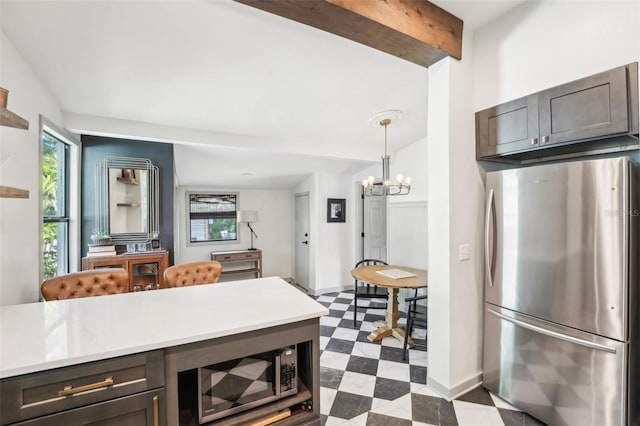 kitchen featuring light countertops, a chandelier, lofted ceiling with beams, stainless steel appliances, and dark floors