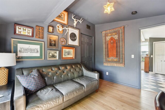 living room featuring lofted ceiling, visible vents, and light wood finished floors