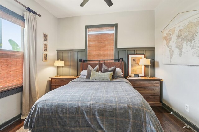 bedroom featuring baseboards, a ceiling fan, a decorative wall, and dark wood-style flooring