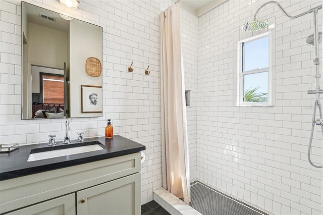 full bathroom with vanity, tile walls, backsplash, a stall shower, and visible vents