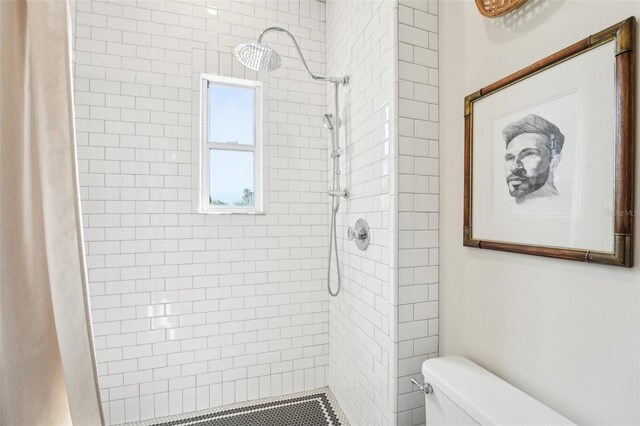 bathroom featuring a tile shower and toilet
