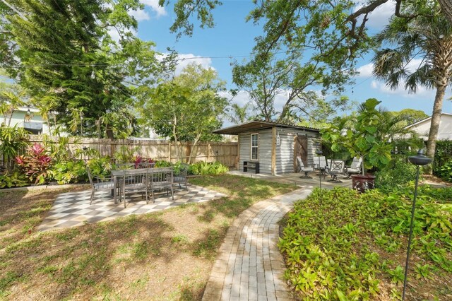 view of yard featuring fence, an outdoor structure, and a patio area