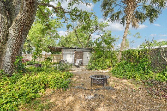 view of yard with an outbuilding, an outdoor fire pit, and fence