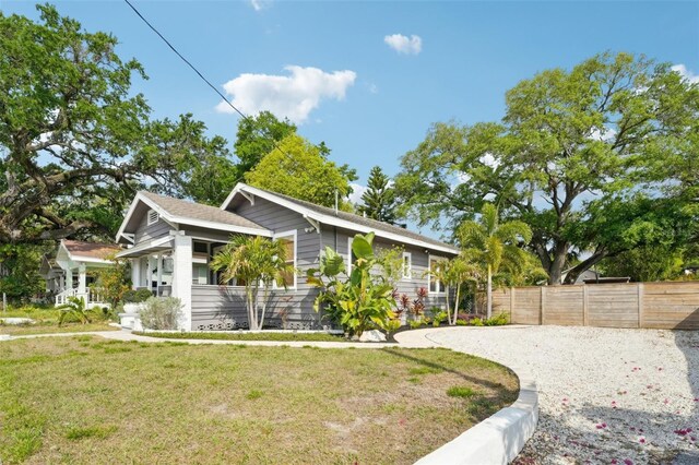 view of front of home featuring fence, a front lawn, and gravel driveway