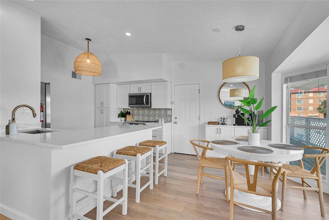 2116/2114 1st St, Indian Rocks Beach, FL 33785 - kitchen featuring stainless steel microwave, a sink, a textured ceiling, tasteful backsplash, and white cabinets