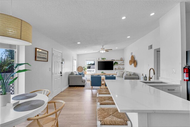 2116/2114 1st St, Indian Rocks Beach, FL 33785 - kitchen with a sink, a textured ceiling, a peninsula, light countertops, and light wood-style flooring