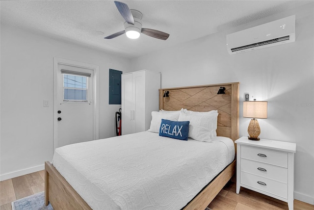 2116/2114 1st St, Indian Rocks Beach, FL 33785 - bedroom with a wall mounted AC, light wood-style flooring, electric panel, ceiling fan, and baseboards