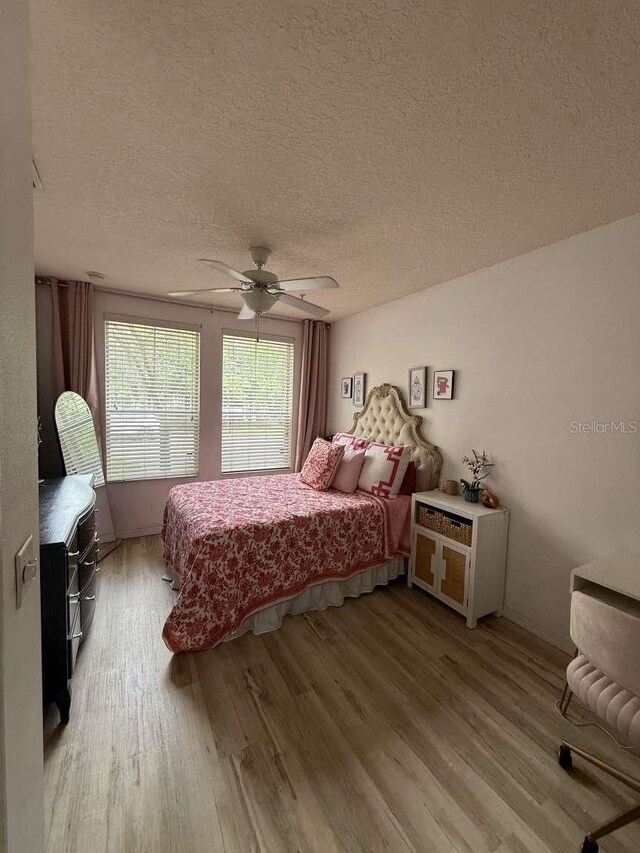 1185 SW 9th Rd Unit 107, Gainesville, FL 32601 - bedroom with light wood-type flooring, ceiling fan, and a textured ceiling