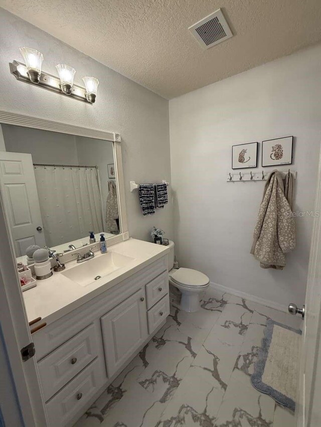 1185 SW 9th Rd Unit 107, Gainesville, FL 32601 - full bathroom featuring a textured ceiling, visible vents, marble finish floor, toilet, and vanity