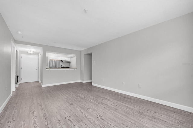 unfurnished living room with baseboards and wood finished floors