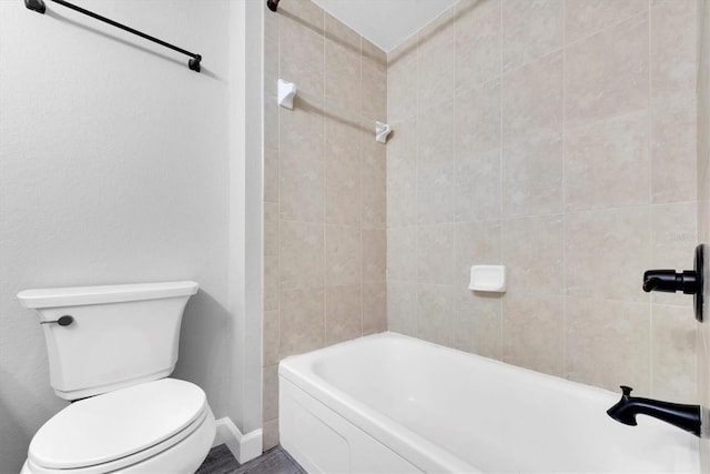 bathroom with toilet, tub / shower combination, and baseboards