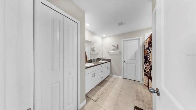 bathroom with a sink, double vanity, visible vents, tile patterned flooring, and a closet