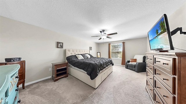 bedroom with a ceiling fan, baseboards, a textured ceiling, and light colored carpet