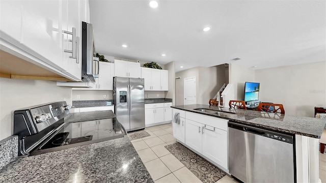 kitchen featuring white cabinets, stainless steel appliances, a sink, a center island with sink, and light tile patterned floors