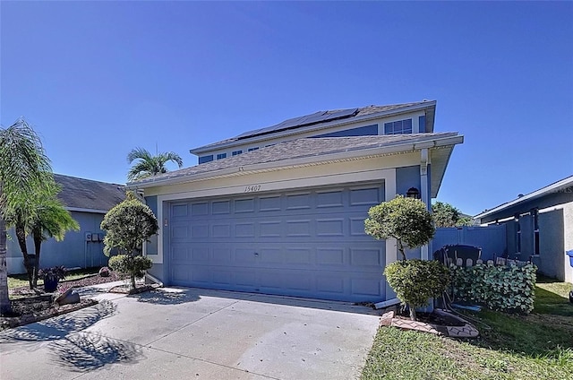 view of front facade featuring solar panels, an attached garage, fence, and concrete driveway