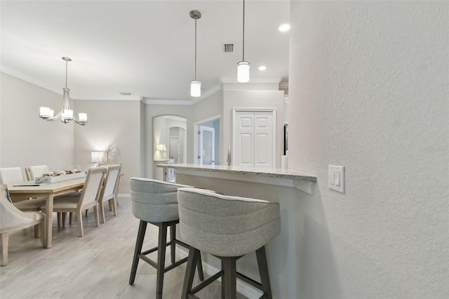 12379 Amica Loop, Venice, FL 34293 - kitchen featuring a textured wall, ornamental molding, arched walkways, light stone counters, and a breakfast bar