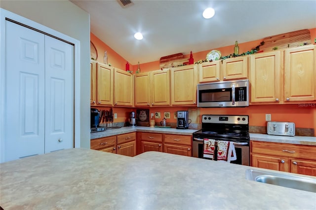 kitchen featuring vaulted ceiling, light countertops, a sink, and stainless steel appliances