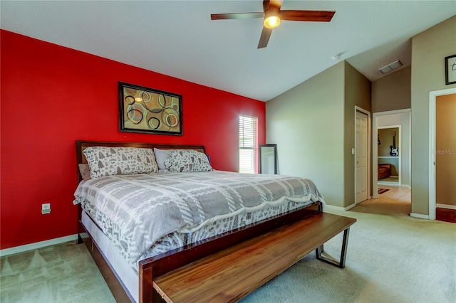 carpeted bedroom featuring lofted ceiling, baseboards, an accent wall, visible vents, and a ceiling fan