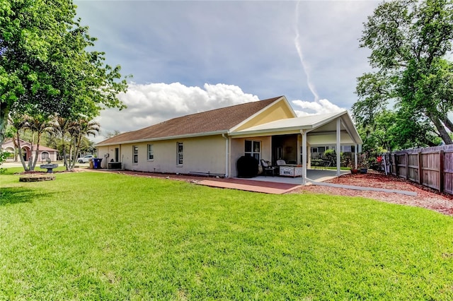 back of property with stucco siding, fence, a lawn, and a patio area