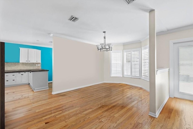 unfurnished dining area featuring ornamental molding, baseboards, visible vents, light wood-style flooring, and a notable chandelier