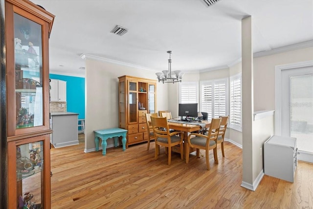 dining area featuring visible vents, light wood-style flooring, ornamental molding, and a chandelier