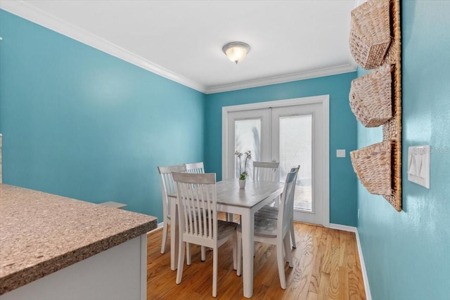 dining room featuring baseboards, ornamental molding, french doors, and light wood finished floors