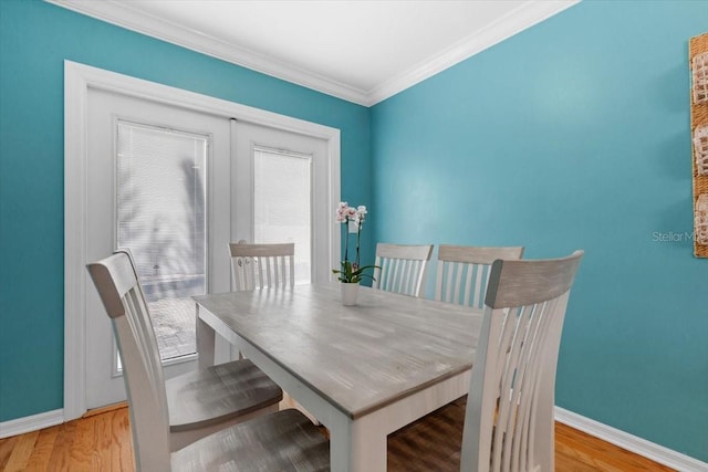 dining room with crown molding, baseboards, and light wood-type flooring