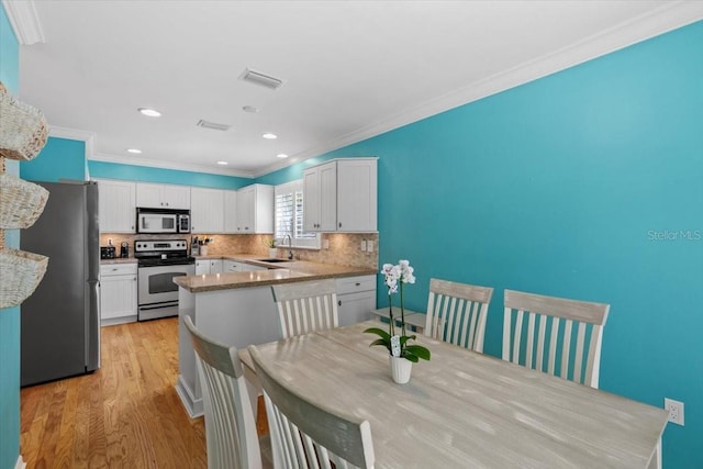 kitchen featuring white cabinetry, light wood-type flooring, decorative backsplash, visible vents, and appliances with stainless steel finishes