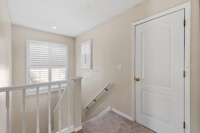 stairs with baseboards, carpet, and a textured ceiling