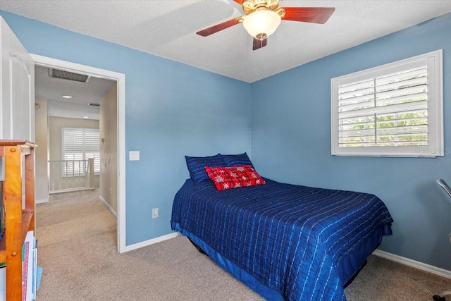 carpeted bedroom featuring a ceiling fan, a textured ceiling, baseboards, and visible vents