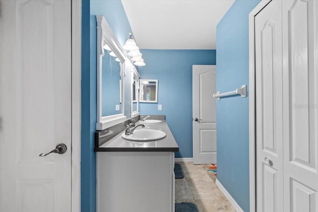 full bath with double vanity, baseboards, a sink, and tile patterned floors