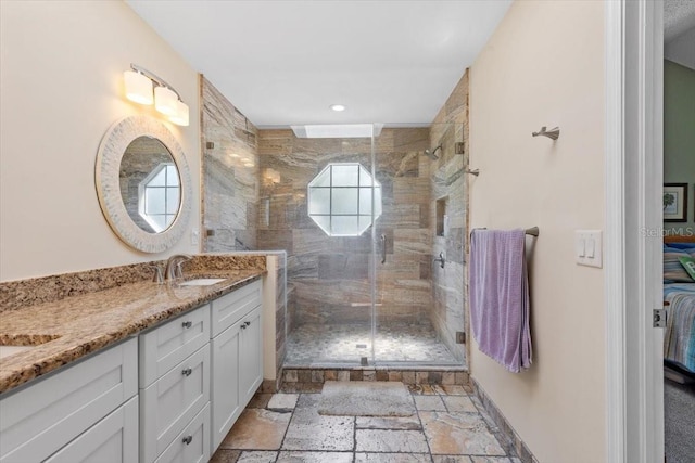 full bath featuring vanity, baseboards, a stall shower, stone tile flooring, and ensuite bathroom