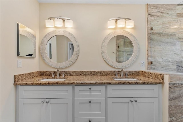 full bathroom with a shower with door, double vanity, and a sink