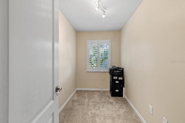 carpeted spare room featuring baseboards and a textured ceiling